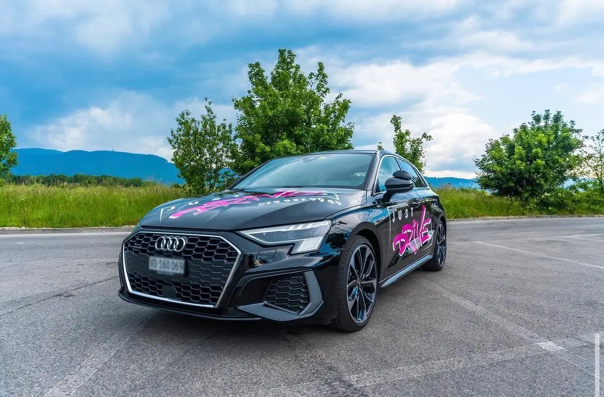 Audi A3 de l’auto-école Just Drive, vue de trois quarts avec son logo magenta