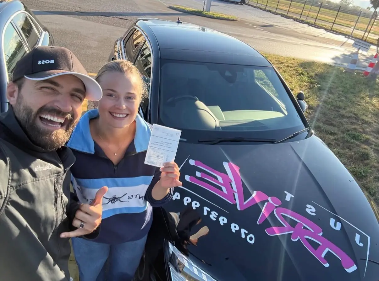 Mergim with his student in a blue polo shirt after passing the driving test.