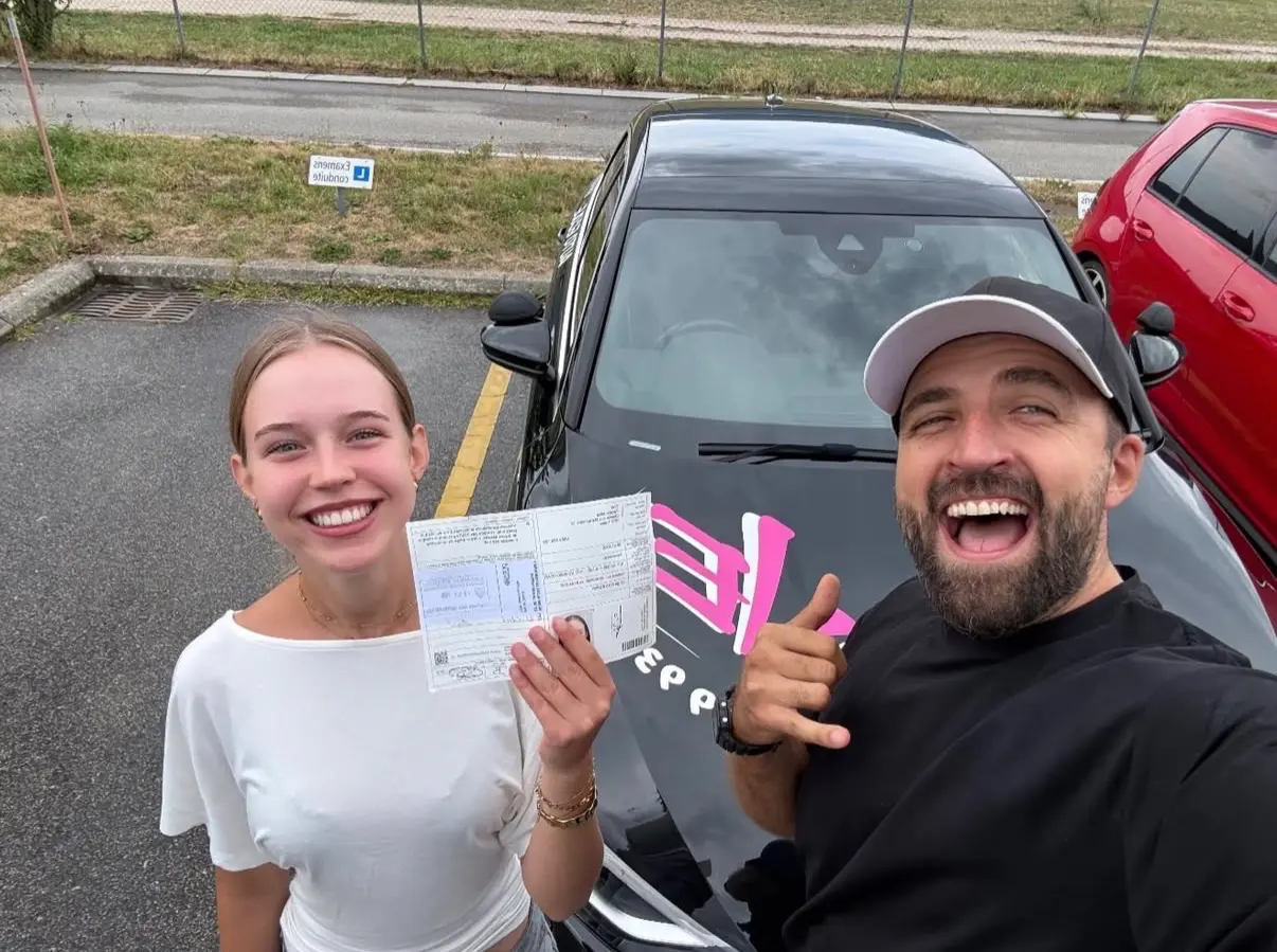 Mergim and his student in a white T-shirt celebrating a driving test pass.