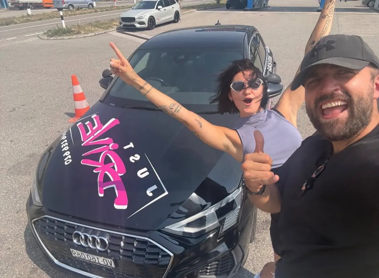 Celebrating a driving test pass at Just Drive with Mergim, arms raised.