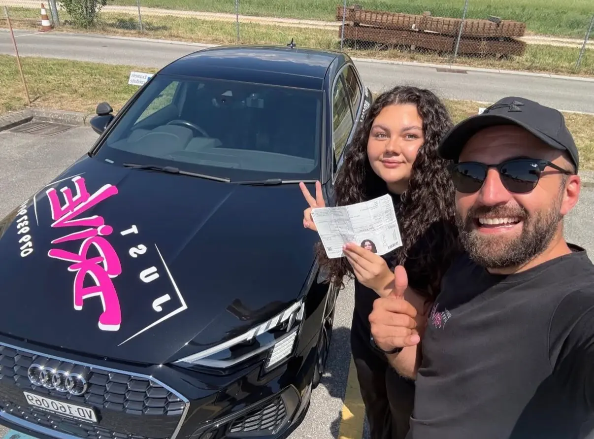 A photo with Mergim beside the Just Drive Audi after passing the driving test.