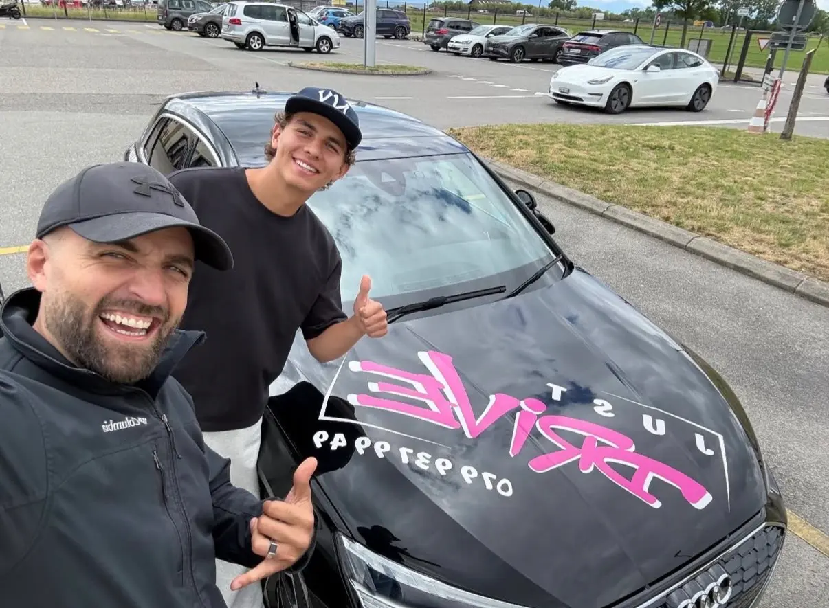 Mergim and his student wearing a cap beside the Just Drive car.