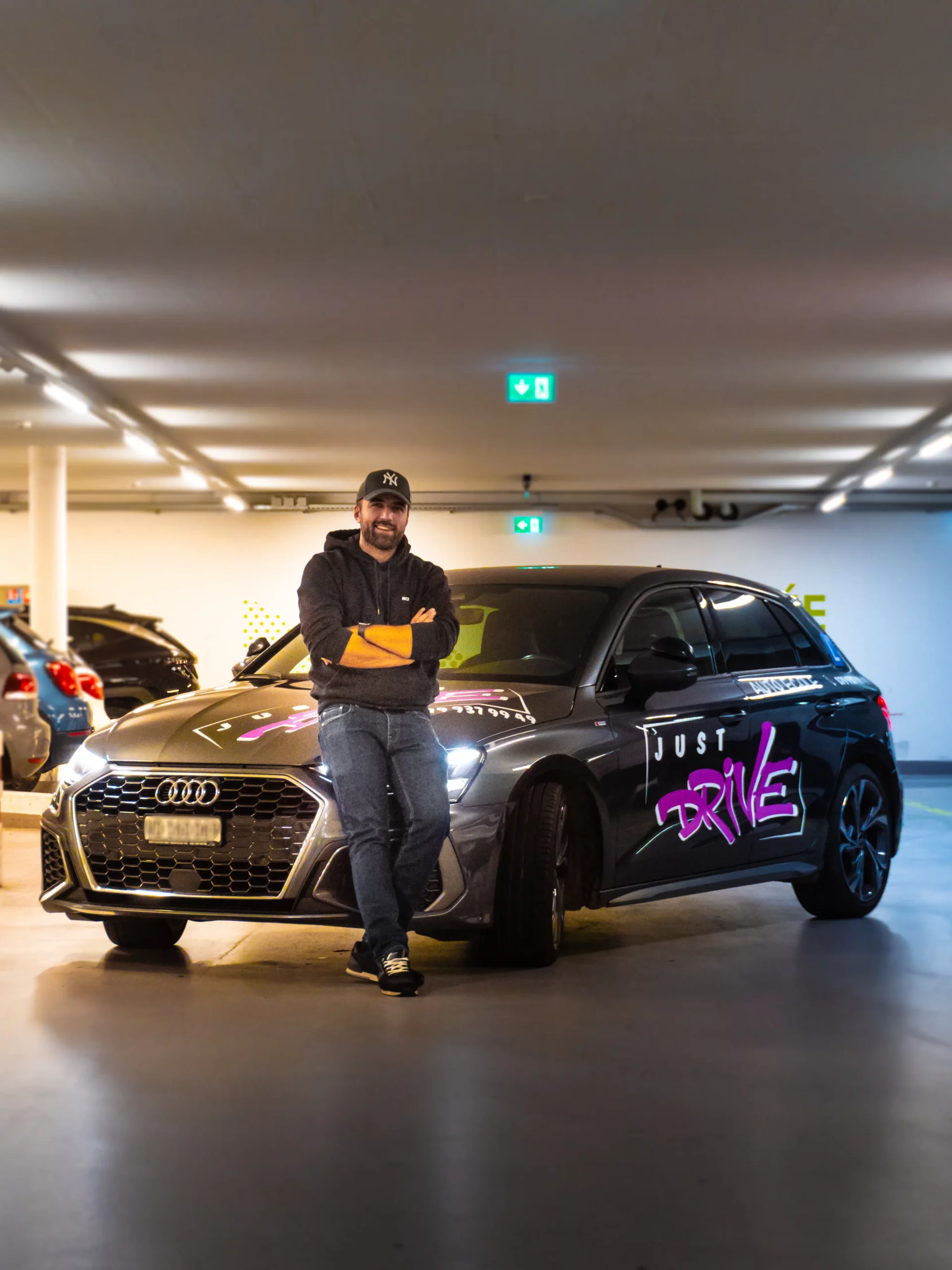 Mergim, your Just Drive driving instructor, beside his Audi in Nyon